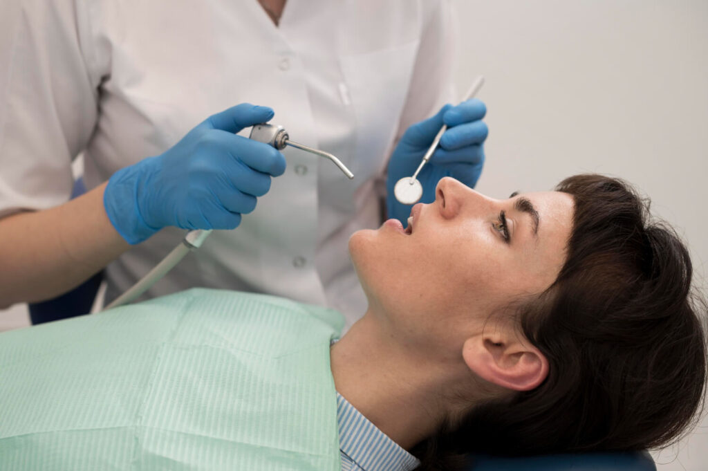 Dentista usa espelho clínico em paciente para avaliar o que causa dor em dente com canal tratado na Paridaens Odontologia em Sumaré.